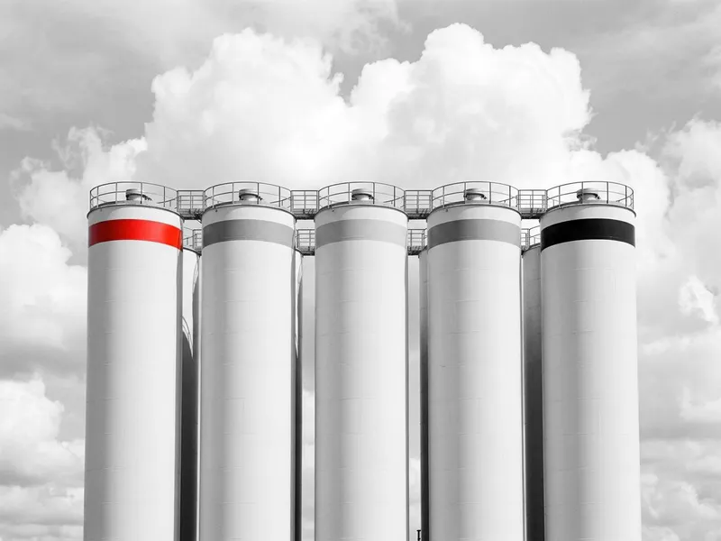 A row of industrial silos against a cloudy sky
